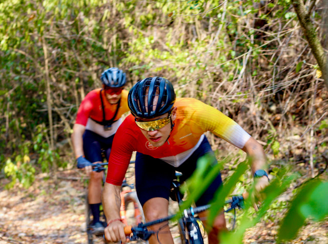 Ciclista con un jersey naranja montando entre la naturaleza